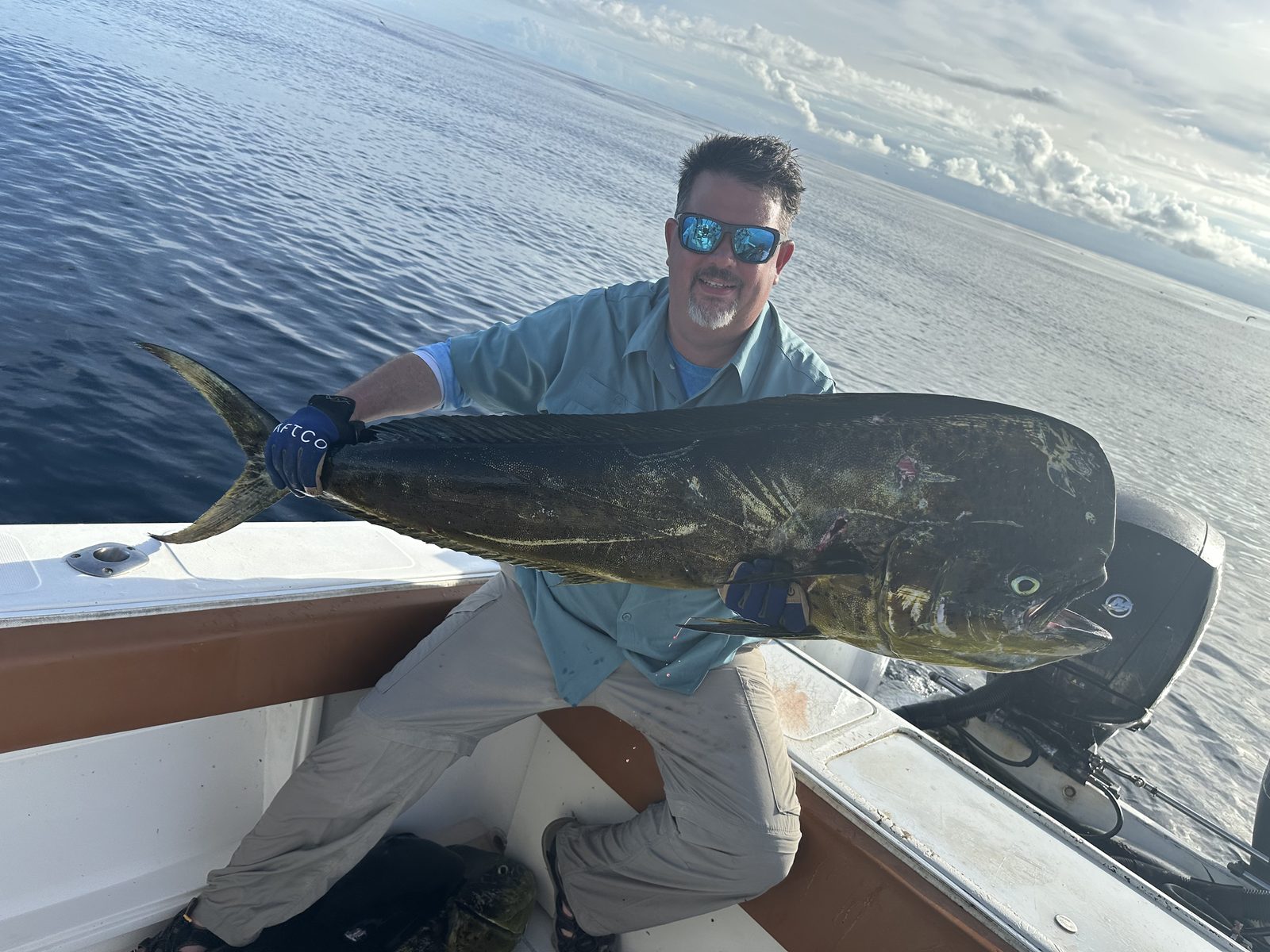A man holding a large mahi-mahi on a boat